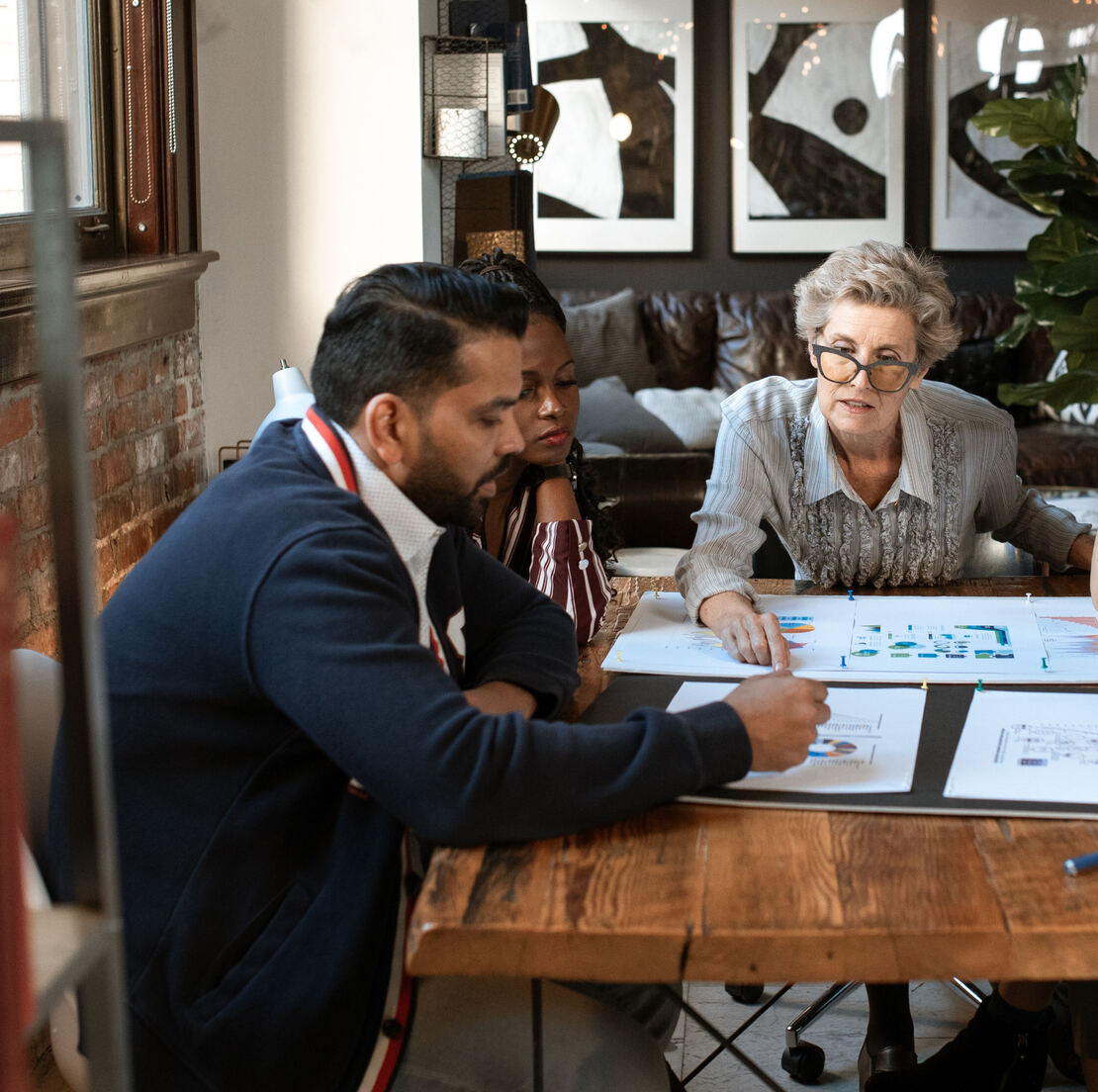 Three people reviewing documents together around a wooden table