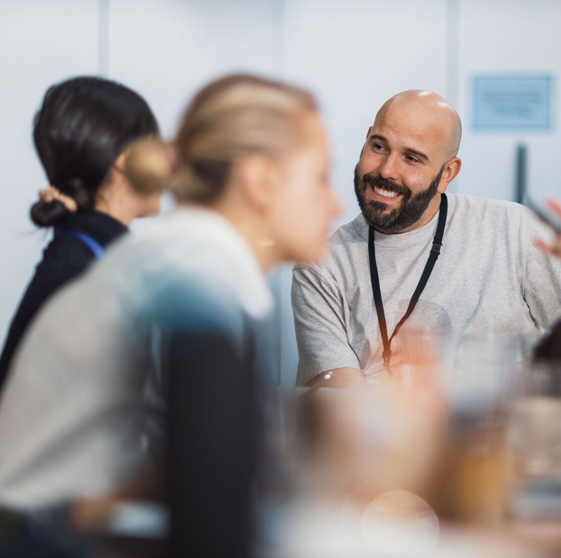 A facilitator smiling at a table of attendees in conversation